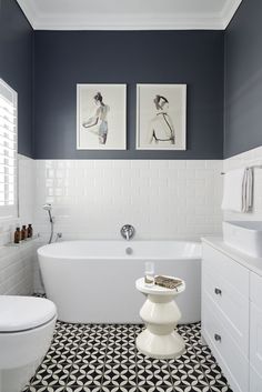 a white and black bathroom with two pictures on the wall