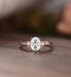 a close up view of a ring with a white diamond in the center on a wooden surface