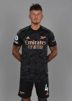 a soccer player poses for a photo in his black uniform with the name emirates fly better on it