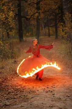 a woman is dancing with fire in the woods