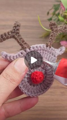 a person is holding a crocheted reindeer ornament with a red nose