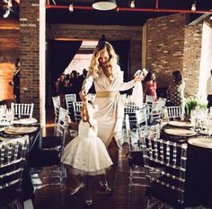 a woman in a white dress is walking through a room filled with tables and chairs