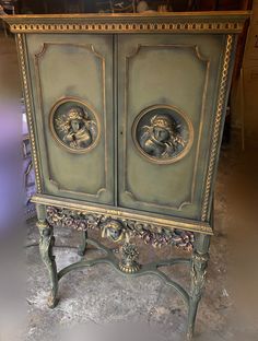 an antique cabinet with two doors and carvings on the front, sitting in a garage