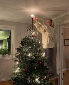 a woman standing on top of a christmas tree holding a sparkler in her hand