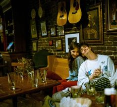 two people sitting in a room with guitars hanging on the wall