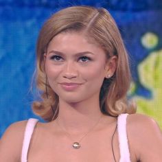 a woman with blonde hair wearing a white dress and necklace on the set of tv talk show