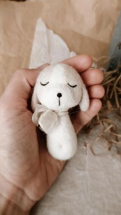 a hand holding a small stuffed animal with eyes closed and one eye closed, while the other is sleeping