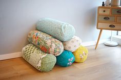 a pile of pillows sitting on the floor next to a dresser