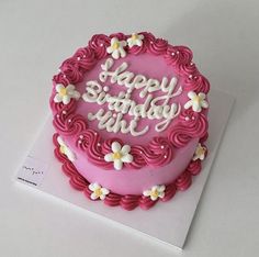 a birthday cake with pink frosting and white flowers