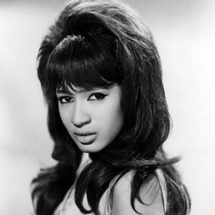 an old black and white photo of a woman with long dark hair wearing a dress