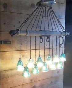 a chandelier made out of glass bottles hanging from the side of a wooden wall