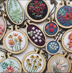 embroidered flowers are displayed on different types of pendants, including daisies and poppies