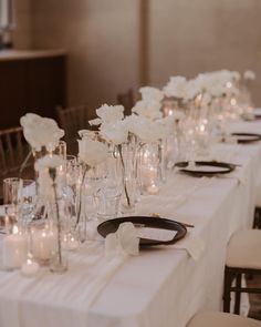 a long table is set with white flowers and candles for a formal dinner or reception