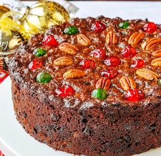 a chocolate cake topped with nuts and cherries on top of a white platter