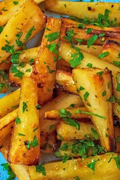 cooked french fries with parsley on top, sitting on a blue and white plate