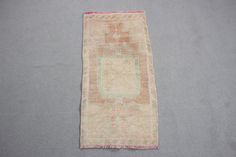 an old rug is laying on the floor in front of a gray wall with a pink border