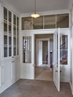 an empty room with white cabinets and glass doors on both sides, leading to the second floor