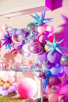 balloons and streamers are hanging from the ceiling in front of a pink brick wall