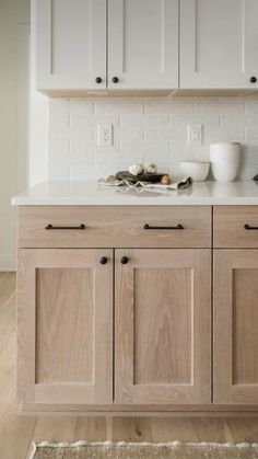 a kitchen with wooden cabinets and white counter tops on top of a hard wood floor