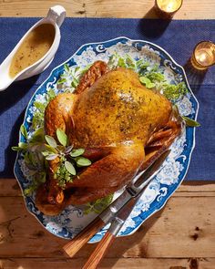 a roasted turkey on a blue and white platter with silverware next to it