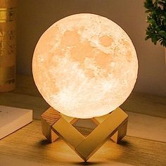 the moon lamp is sitting on top of a wooden stand