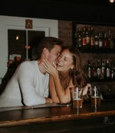 a man and woman sitting at a bar hugging each other