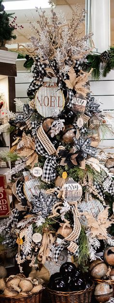 a christmas tree decorated with black and white ribbon, pine cones, and other holiday decorations