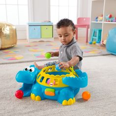 a young boy playing with a toy elephant on the floor in a playroom filled with toys