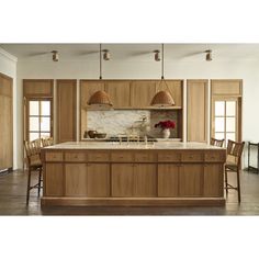 a large kitchen with wooden cabinets and marble counter tops, along with an island in the middle