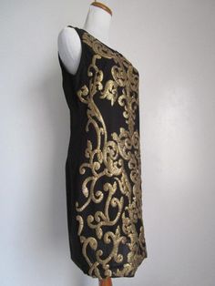 "This is a Glamorous Vintage Modern 1963DEX Made in INDIA Black Polyester and Golden Metallic Gold Sequin Embellished Shift Knee Midi Dress Cocktail Party Evening Special Occasion Size S M The style is a fully lined, shift dress with side invisible zipper, and heavily embellished metallic gold knee sequins front and back (never sit on sequins!). condition there is 1 very tiny hole/cut on the side of the dress, but it's not obvious, only if you stare at it really closely. Other than that, this lo Gold Embroidered Sleeveless Dress, Gold Embellished Mini Dress For Festive Occasions, Festive Gold Embellished Mini Dress, Black Embellished Sheath Dress, Black Dress With Gold Embroidery For Party, Black Evening Dress With Gold Embroidery, Black Dress With Gold Embroidery For Festive Occasion, Festive Black Dress With Gold Embroidery, Black Sleeveless Festive Dress