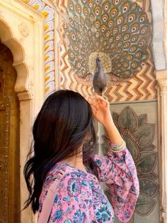 a woman is looking at a bird on the wall