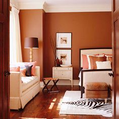 a living room with brown walls and zebra print rugs on the hardwood flooring