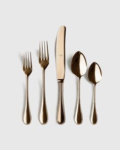 four forks, two knives and three spoons on a white surface with one fork in the middle