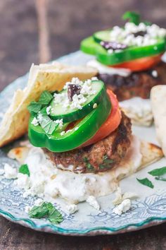 a blue plate topped with a burger covered in cheese and veggies next to tortilla chips