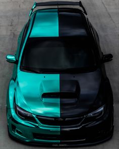 a green and black car is parked on the side of the road with another color blocking it