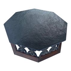 an octagonal black stone table top on a wooden stand with metal rings around the edges