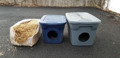 two trash cans sitting next to each other on top of a street near a fence