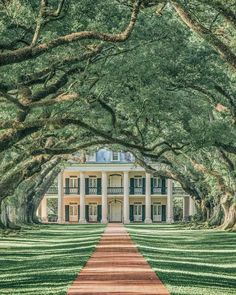 a large white house surrounded by trees in the middle of a field with green grass