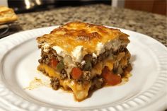 a piece of lasagna on a white plate sitting on a counter with a fork