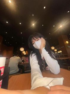 a woman sitting at a table with a napkin covering her face