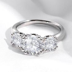 three stone diamond ring setting on white cloth with soft light coming in from the side