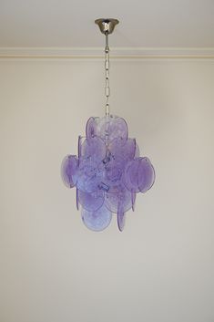 a purple chandelier hanging from the ceiling in a room with white walls and flooring