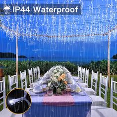 the table is set with flowers and white chairs under an umbrella that has rain falling down on it