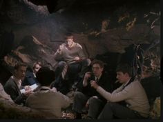 a group of men sitting around each other in a cave