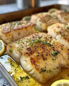 some fish and lemons on a pan with seasoning sprinkled on them