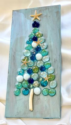 a christmas tree made out of marbles and starfish on top of a white sheet