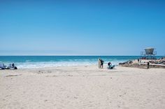 some people are standing on the beach by the water