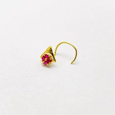 a pair of gold earrings with pink stones on the end, sitting on a white surface