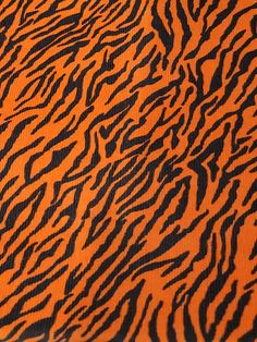 an orange and black animal print fabric with very thin lines on the top part of it