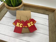 pair of kansas kcs jersey earrings on wooden table next to potted plant and card board